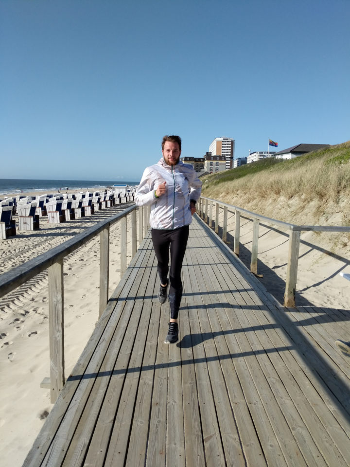 Philipp läuft über eine Holzpromenade an der Küste